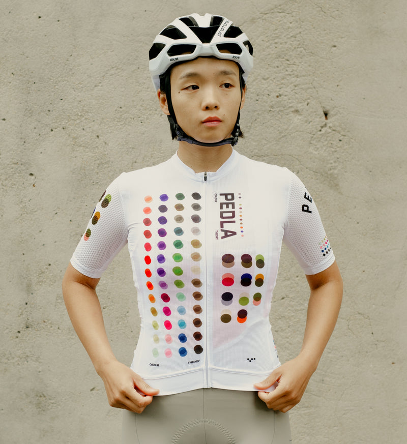 Model wearing the COLOUR THEORY Women's LunaAIR Cycling Jersey in white, highlighting a race-fit design, breathable mesh sleeves, and UPF 35+ sun protection.