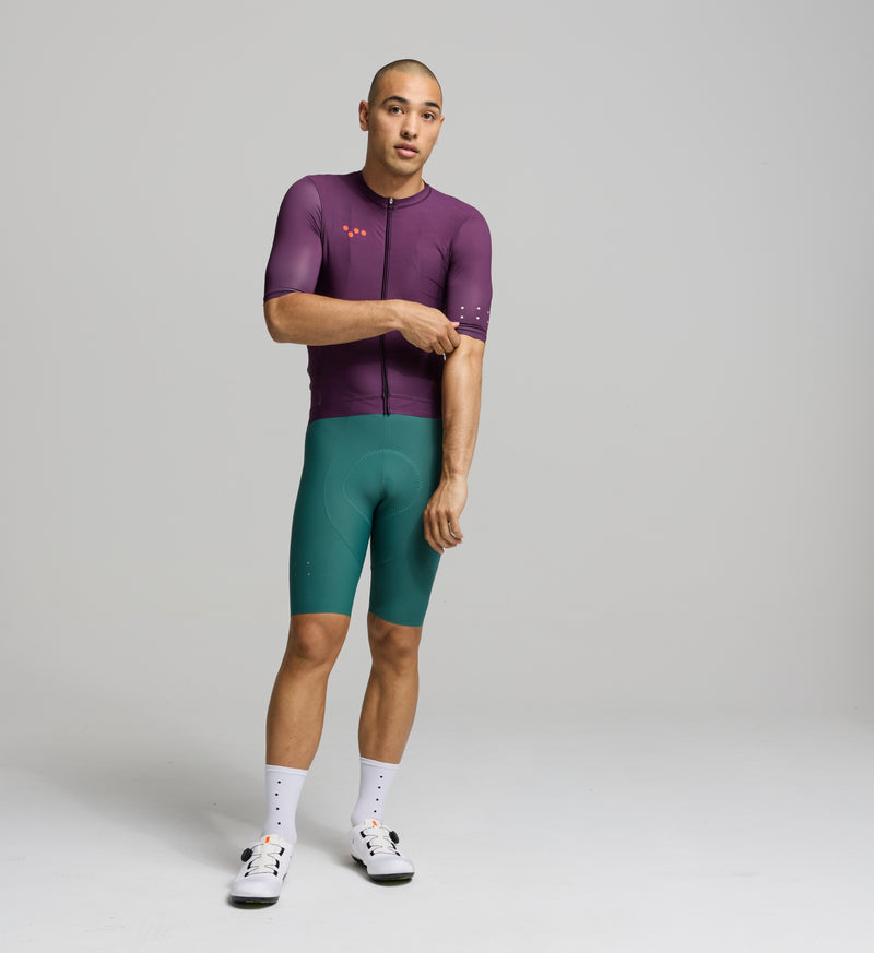 Front view of male cyclist in aubergine Classic Jersey – streamlined silhouette with extended sleeves and low-cut collar for a sleek, modern cycling fit.