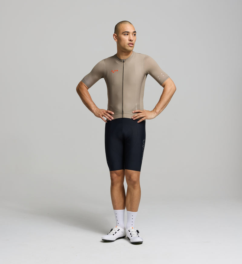 Front view of male cyclist in sandstone Classic Jersey – close-fitting cut with low-profile collar, extended sleeves, and a refined silhouette for endurance comfort.