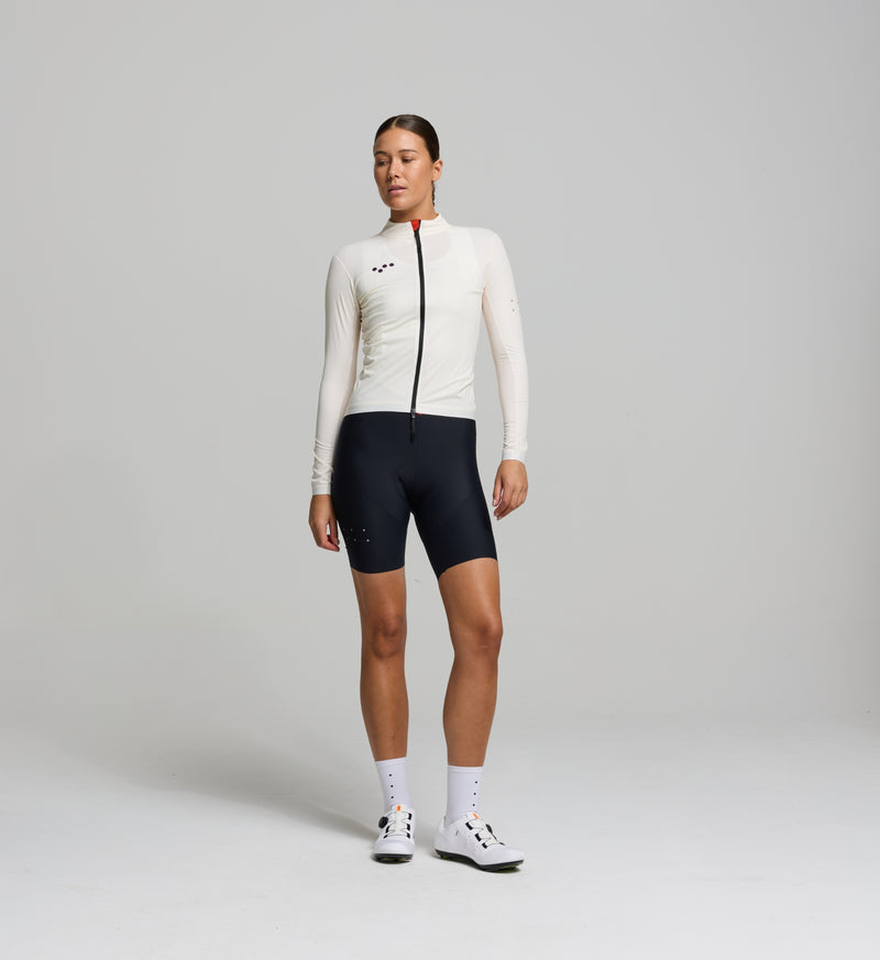 Front view of female cyclist in almond Classic Jacket – streamlined fit with SAB two-way zipper, wind-blocking front panel, and breathable underarm mesh for versatile weather protection.