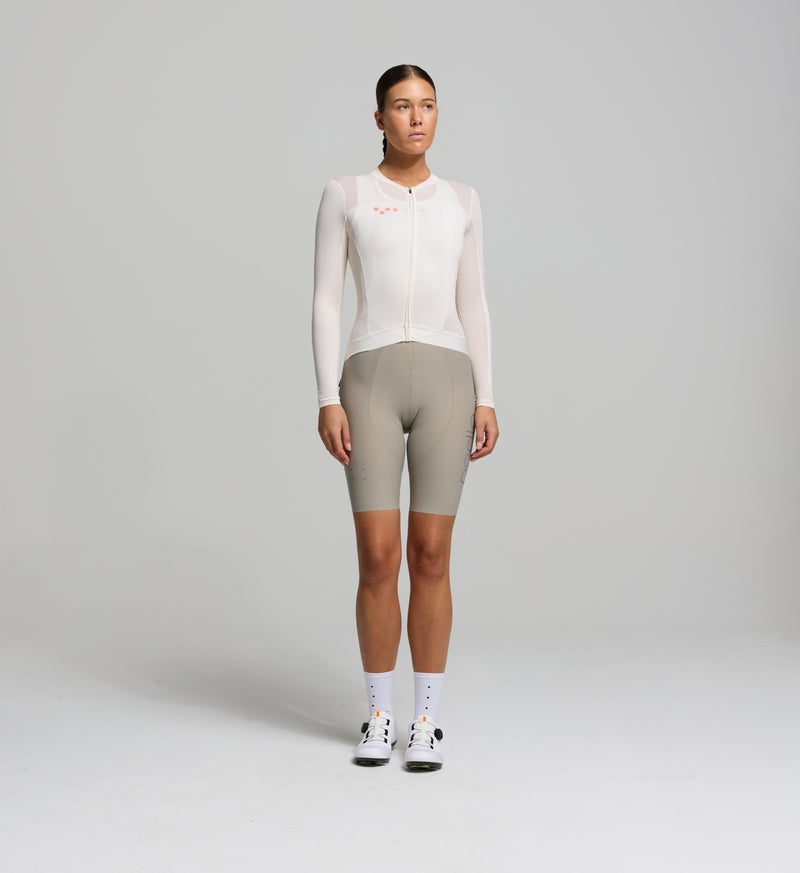 Female cyclist wearing Pedla's almond-coloured long sleeve jersey for summer – aerodynamic, breathable fit with UPF protection.
