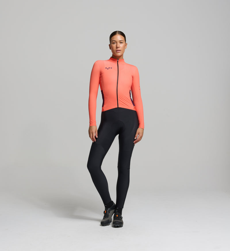 Female cyclist in Pedla’s apricot midweight long sleeve jersey – streamlined front view with articulated sleeves and modern seam design for an aerodynamic, non-restrictive fit during cool-season training.