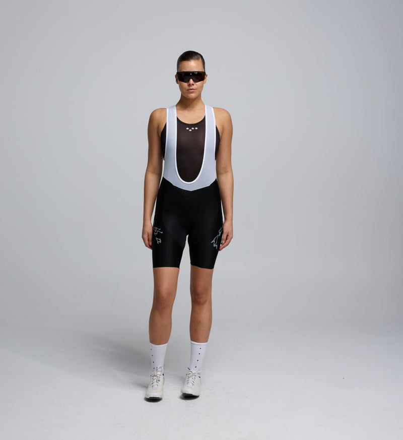Female cyclist wearing black bib shorts from the Lost in Nature collection, showing supportive fit and seamless cuff design.