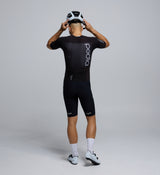 Back profile of the Men's Pro Pursuit Crit Suit – Black, showing sculpted sleeve panels with AeroPRISMA fabric, silicone leg grippers, and ergonomic design for high-speed movement.