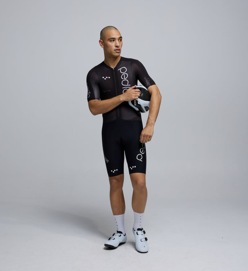 Front-facing image of a male cyclist wearing the Pro Pursuit Crit Suit in Black, highlighting the close-fitting aero cut, low-profile collar, and breathable woven fabric designed for speed.