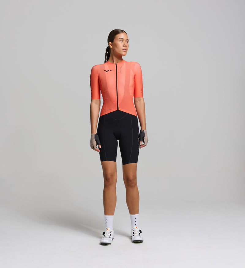Cyclist wearing the Women’s Pursuit AIR Cycling Jersey in Apricot, showcasing its aerodynamic fit, advanced moisture-wicking fabric, and UPF 35+ sun protection for summer cycling.