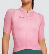 Close-up view of Essentials Women's Air Cycling Jersey in Flamingo on model, detailing the slim low-cut collar with laser-cut garage, stitch-free bonding at sleeve hems, and moisture-wicking fabric for enhanced comfort in hot conditions.