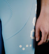 Close-up of women's Pedla SuperFIT 2.0 powder blue cycling bib tights, seamless Italian fabric, zigzag stitch and white dot logo, Elastic Interface chamois, reflective detail, aerodynamic high-performance bib shorts