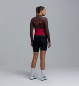 Women's midweight long-sleeve cycling jersey back view, wood-brown with red waist panel, breathable brushed-thermal interior, moisture-wicking, hem gripper, four rear pockets, articulated sleeves for cool-weather layering