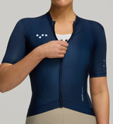 Person wearing a navy cycling jersey with a Pedla logo on a gray background