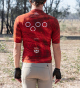 Back view of men’s SuperSYSTEM gravel jersey in desert – rear storage pockets and reflective detailing for visibility during long rides