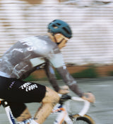 Back view of LOCAL LOOPS Men's Long Sleeve Cycling Jersey in Club Grey on model, featuring a tailored fit, extended sleeves, and soft silicone gripper hem that keep the jersey in place for a streamlined and comfortable ride.