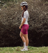 Side view of NatureCAMO Women's Cycling Jersey in Sketch White on model, highlighting the ergonomic fit, silicone gripper hem, and four-way stretch fabric for enhanced flexibility and performance during cycling sessions and training rides.