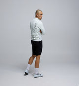 Back view of the Porcelain Deflect 2.0 Jacket, displaying storm-flap-covered rear storage pockets, reflective safety detailing, and dropped hem for full coverage in wet conditions.
