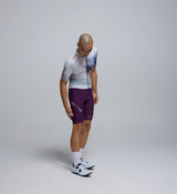 Side view of the Men's AirFoils White Pro Crit Suit worn by a cyclist, highlighting the sculpted AeroPRISMA sleeve, bonded cuff, and streamlined paneling for maximum speed.