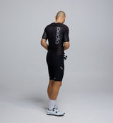 Side profile of the Men's Pro Pursuit Crit Suit – Black, showing sculpted sleeve panels with AeroPRISMA fabric, silicone leg grippers, and ergonomic design for high-speed movement.
