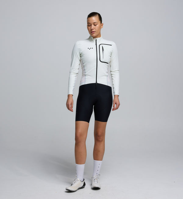 Front view of a female cyclist wearing the Porcelain Deflect 2.0 Jacket, featuring a high-performance fit, chest pocket with waterproof zipper, and clean, aerodynamic styling.