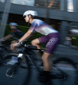 Side view of the Pedla Women's AirFoils White Pro Pursuit Crit Suit on model, highlighting the seamless bonded cuff, contoured panels, and drag-reducing sleeve structure.