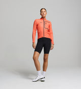 Cyclist wearing the Women’s Pro Deflect 2.0 Cycling Jacket in Apricot, showcasing its high stand collar, streamlined fit, and breathable waterproof fabric.