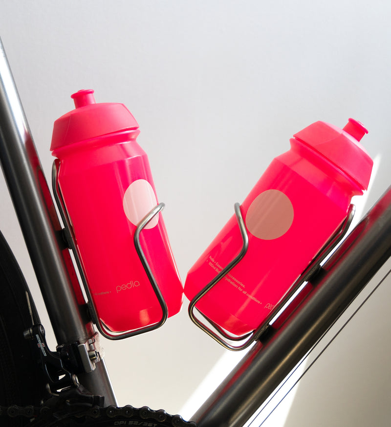 Pink Pedla bidon securely mounted in bike bottle cage; compact, accessible, and perfect for hydration on the move