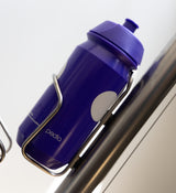 Purple Pedla bidon securely mounted in bike bottle cage; compact, accessible, and perfect for hydration on the move