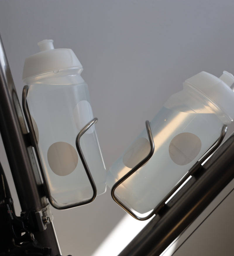 White Pedla bidon securely mounted in bike bottle cage; compact, accessible, and perfect for hydration on the move.
