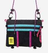 Topo Designs Mountain Accessory Shoulder Bag in Black/Grape, showing front side on model, made from 100% recycled nylon.